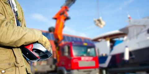 Osoba trzymająca kask na tle maszyn budowlanych